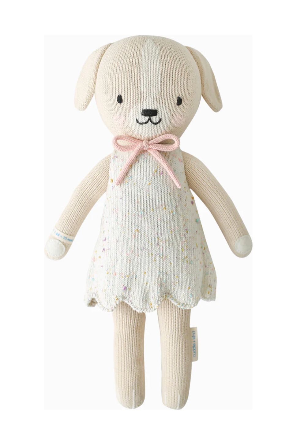 13 inch stuffed dog with speckled dress with scalloped edges and a pink bow.