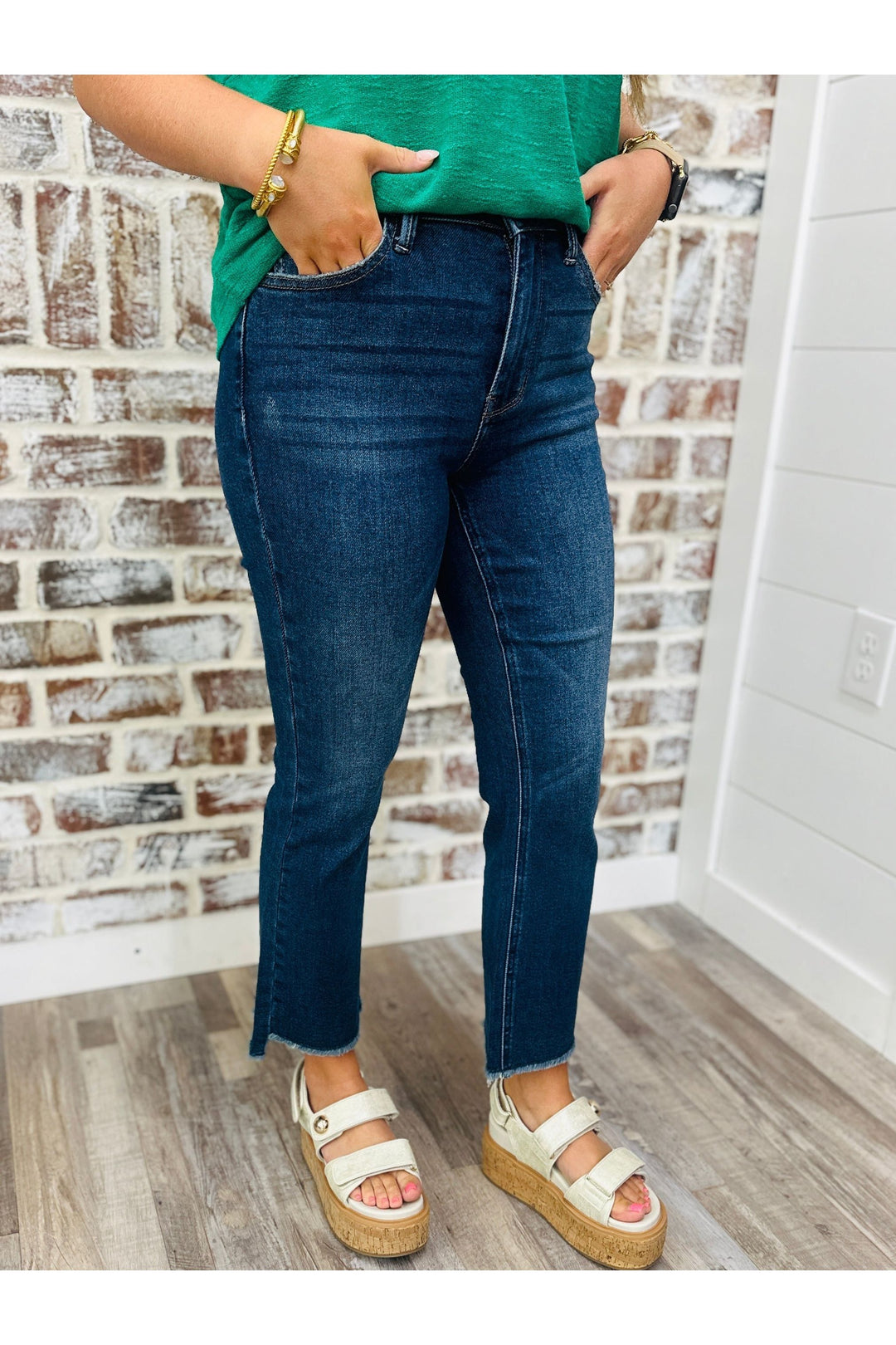 Woman wearing High Waisted Dark Washed straight leg denim pants standing against a brick wall.