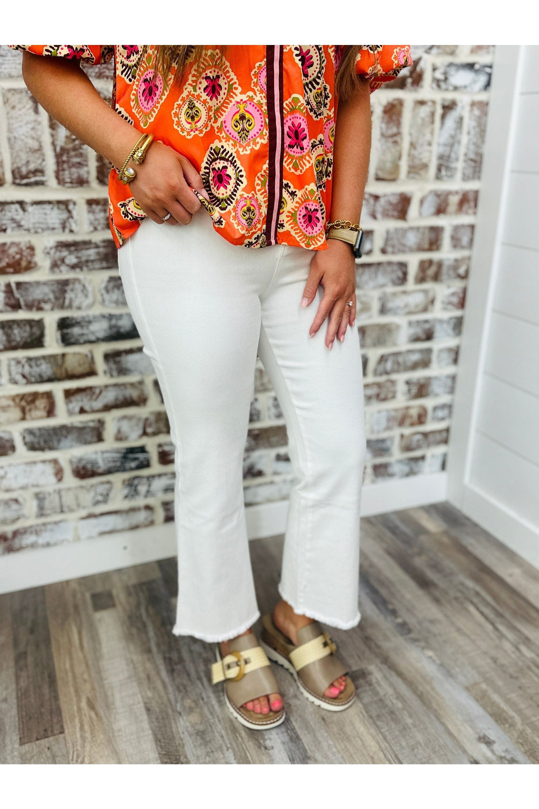 Woman wearing high waisted cropped flare pants standing against a brick wall.