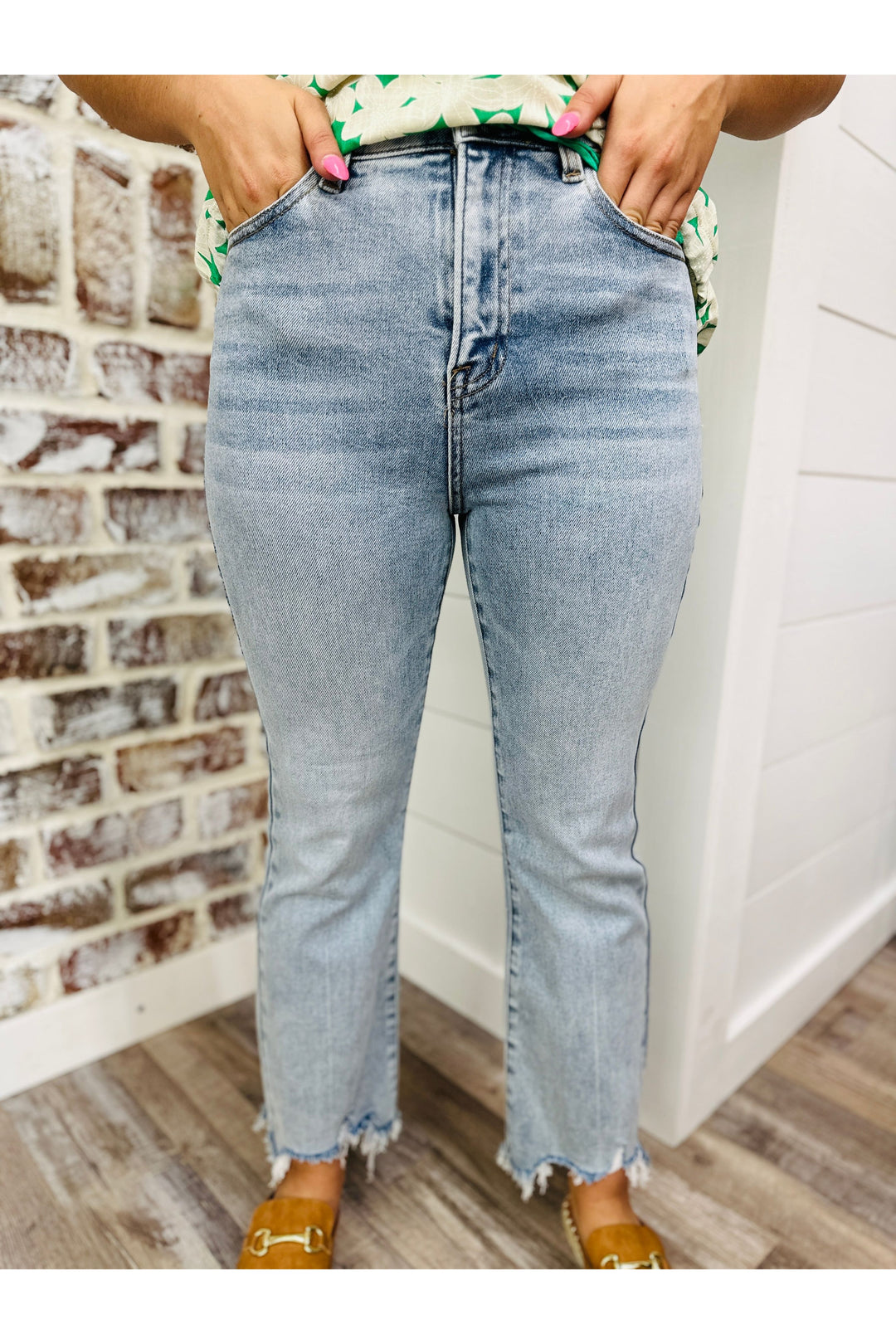 Woman wearing cropped high rise light washed denim jeans with frayed hem.