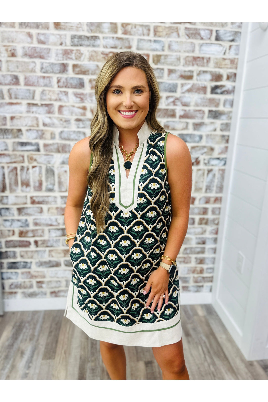 Woman wearing scalloped flowers dress standing against a brick wall. Paired with Black Julie Vos statement necklace. 