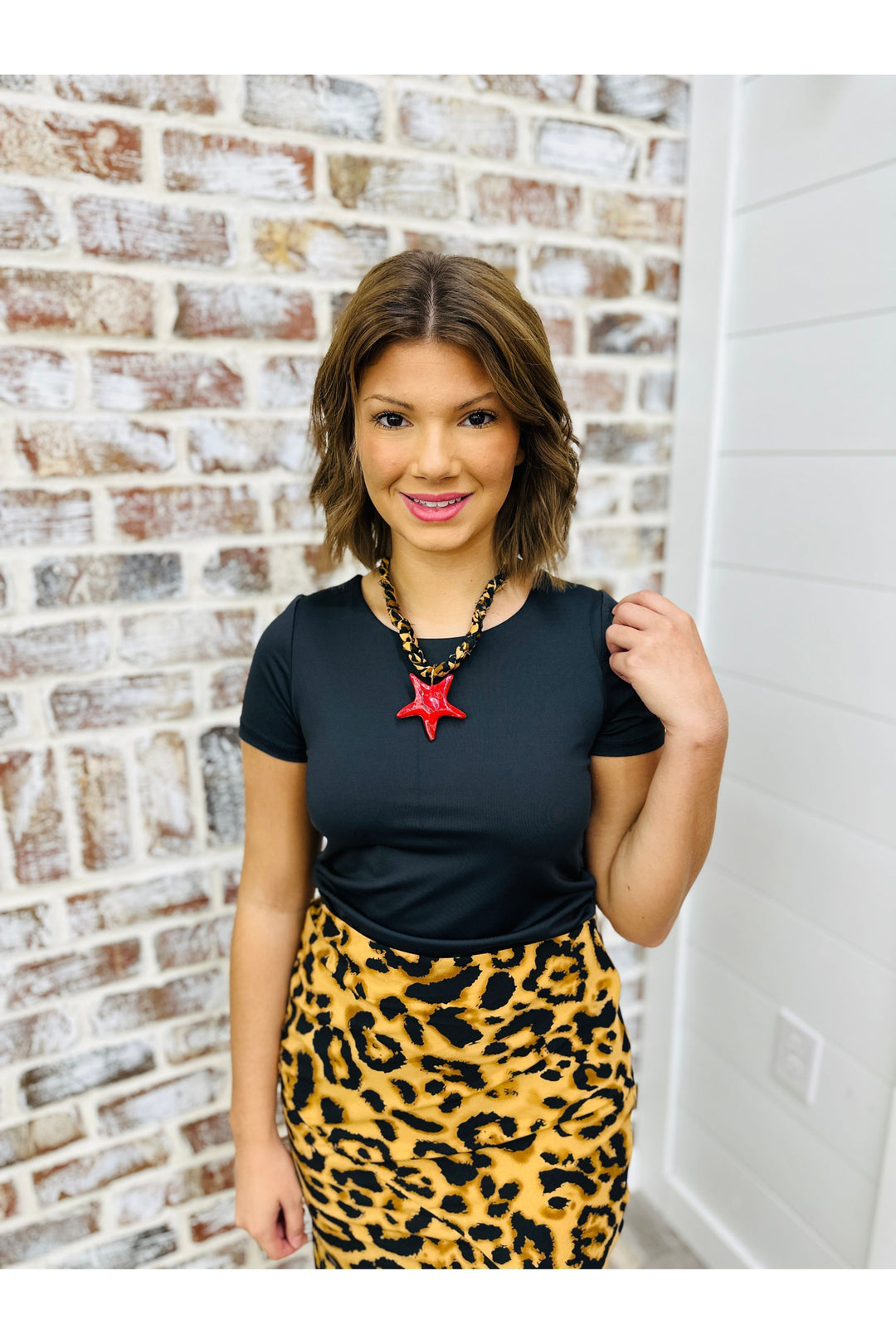 Woman wearing black shirt with cheetah skirt and necklace 
