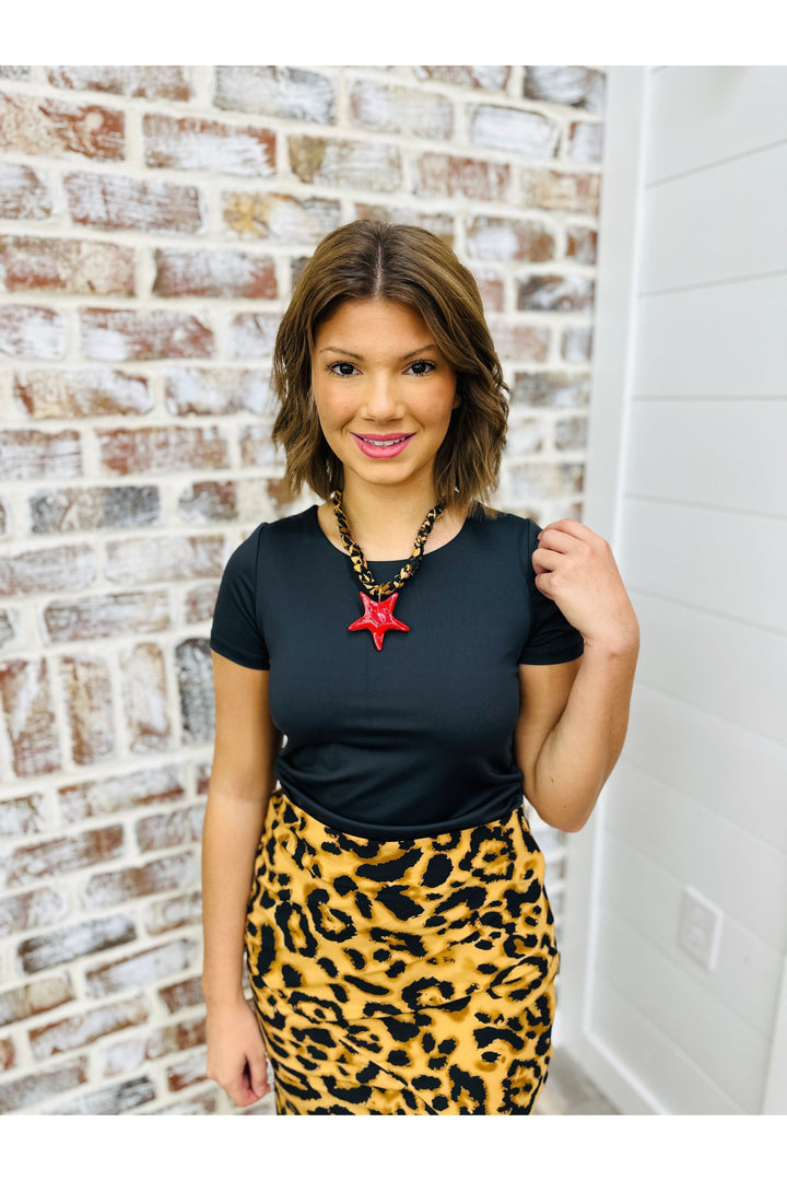 Woman wearing black shirt with cheetah skirt and necklace 