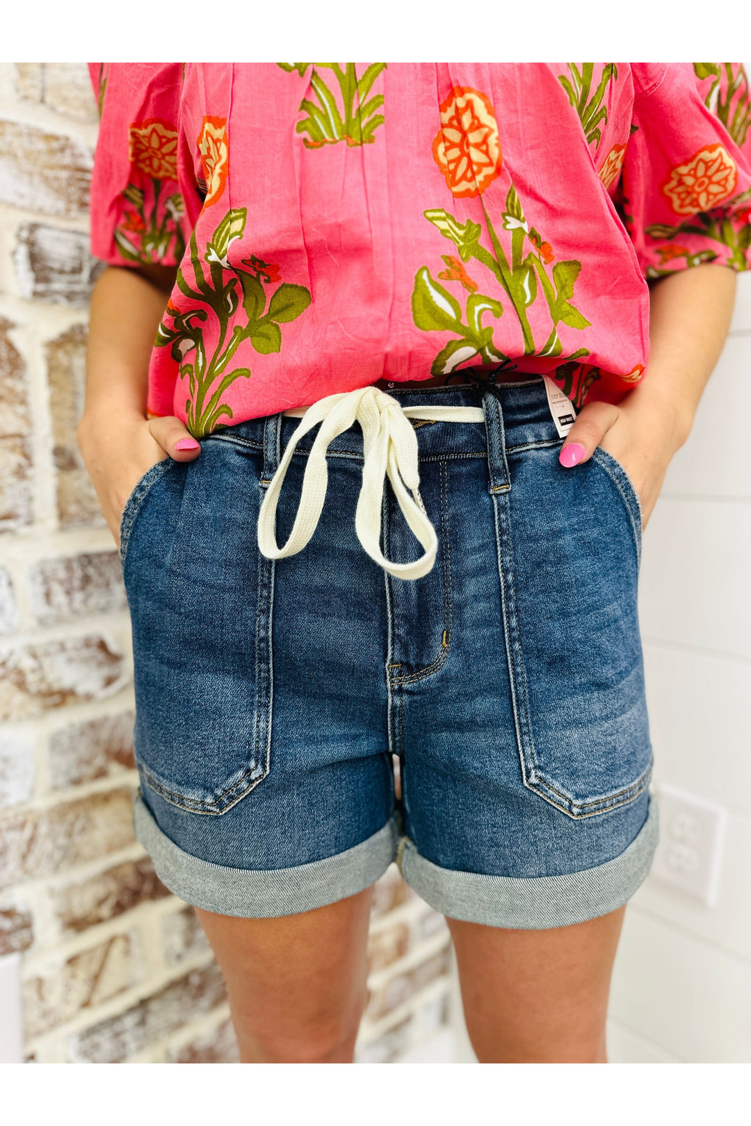 Woman wearing Judy Blue high waisted jogger shorts with adjustable drawstring paired with a pink floral top.