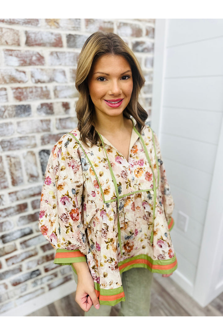 Woman wearing a floral detail top with multicolor accent bands.