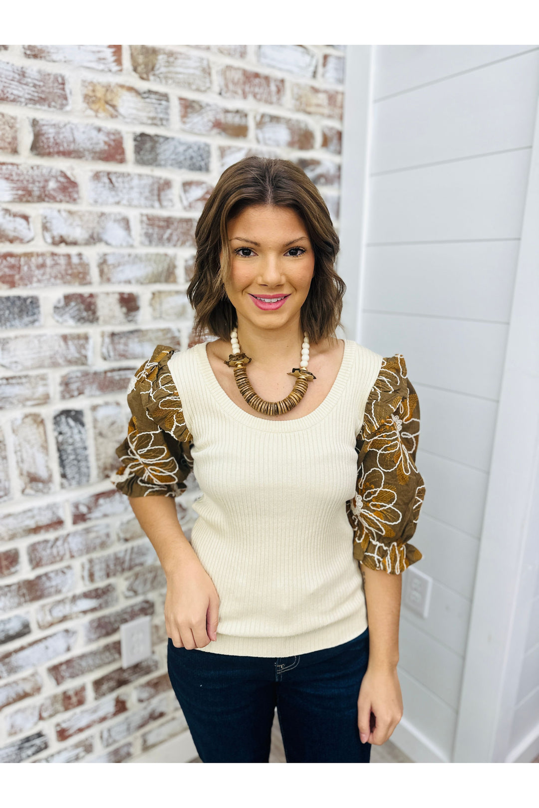 cream colored light weight sweater with brown sleeves and floral design