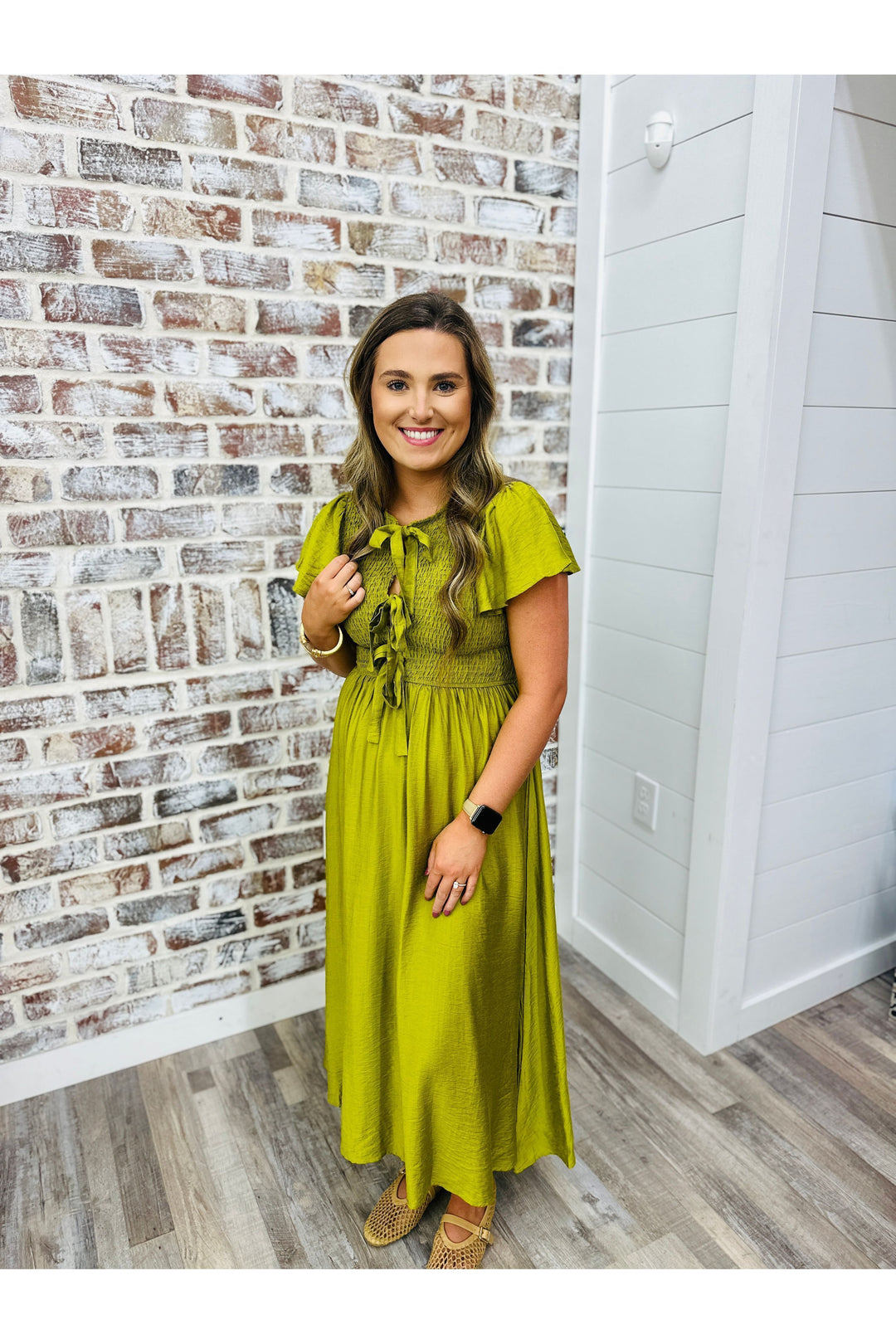 Woman wearing a deep lime midi dress with bow detailing at the top.