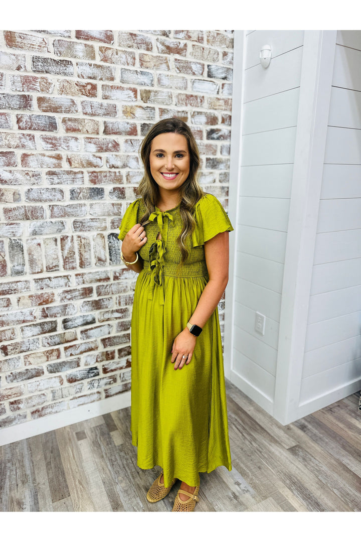 Woman wearing a deep lime midi dress with bow detailing at the top.