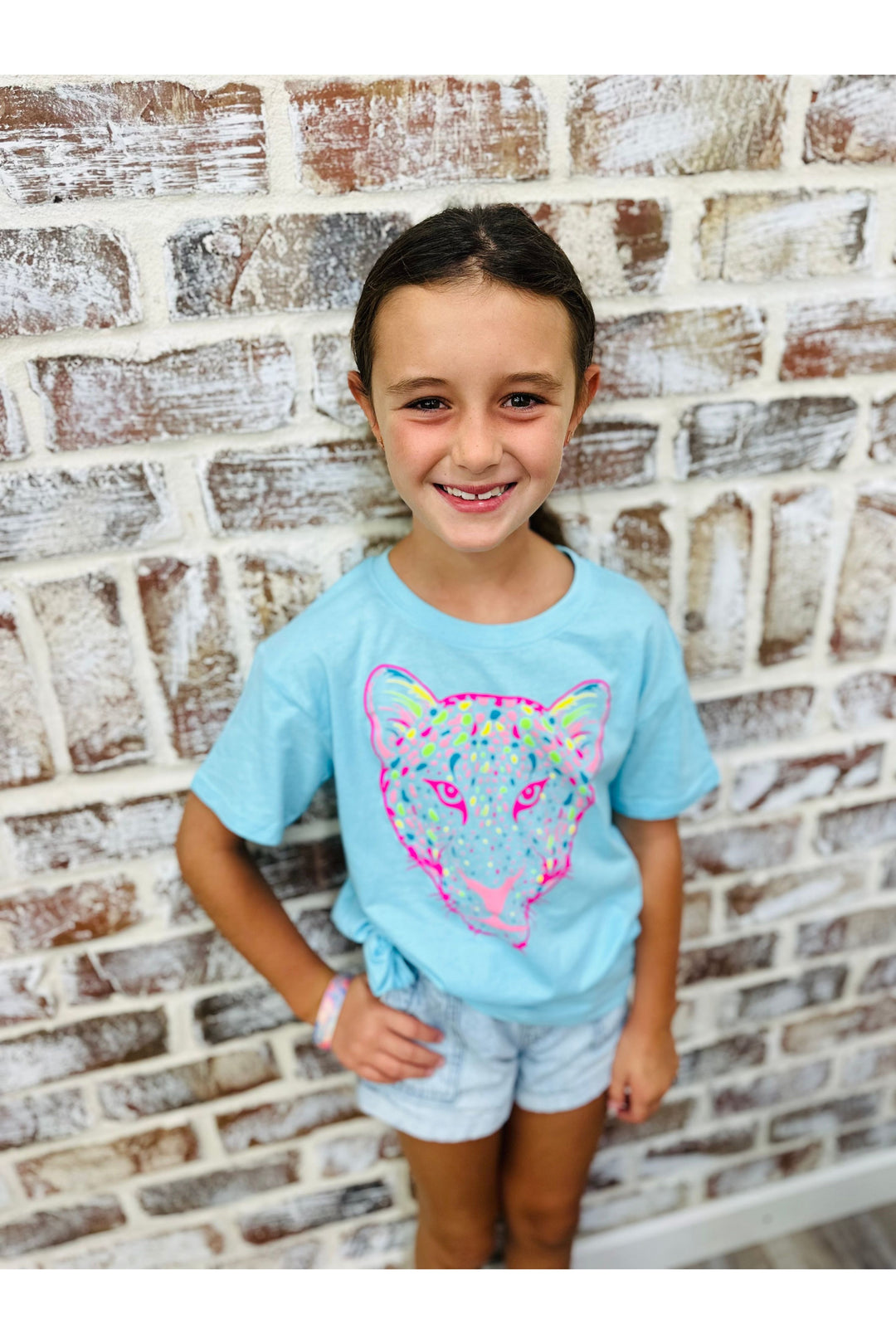 Little girl wearing teal tshirt with colorful tiger image.