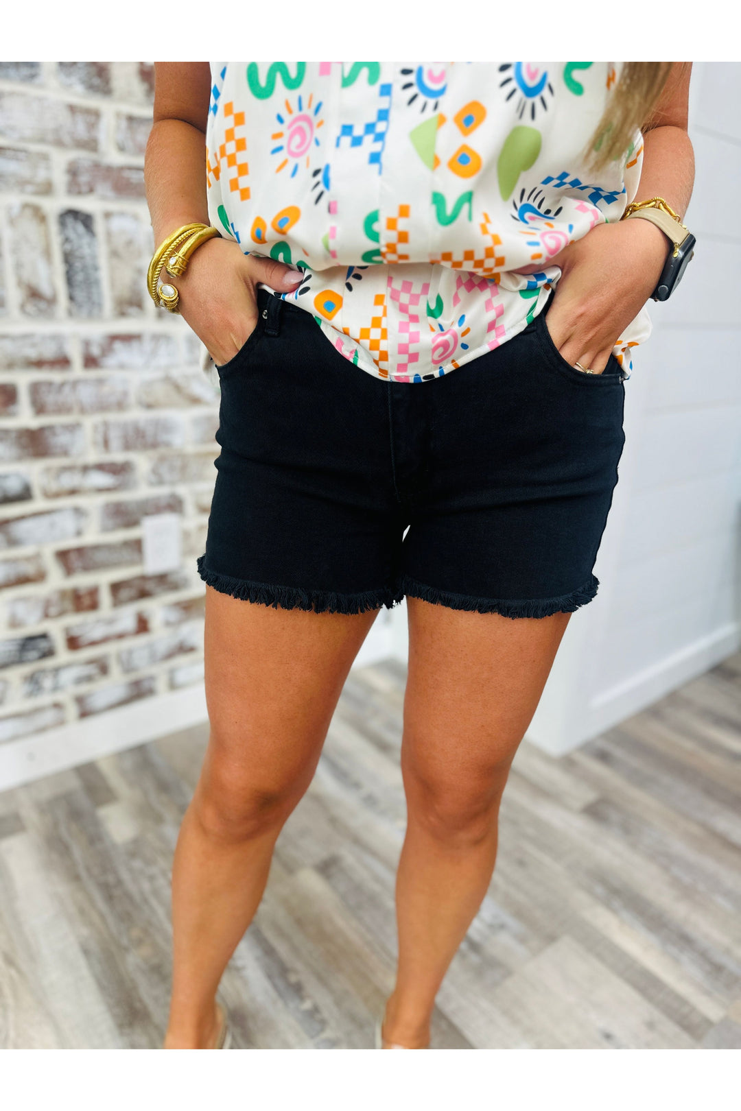 Woman wearing black shorts with frayed edges paired with a printed top.