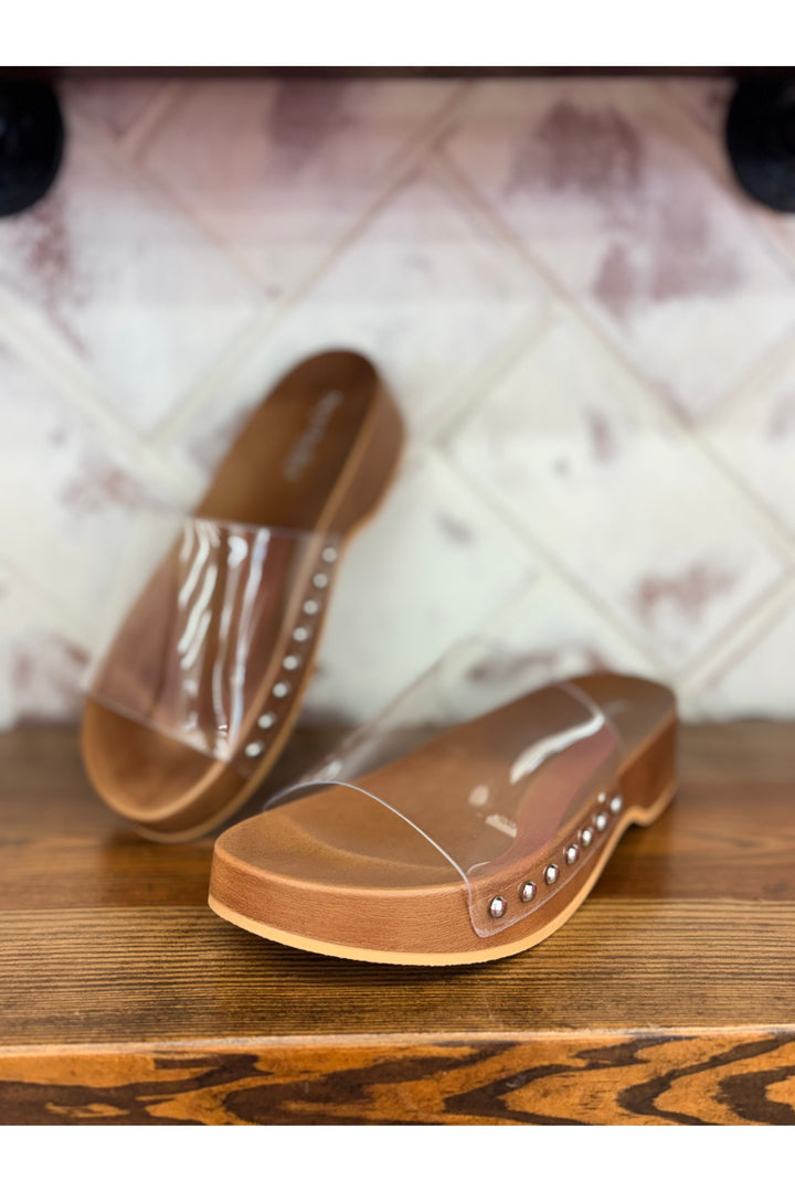 Clear sandal with brown accents on a wooden surface