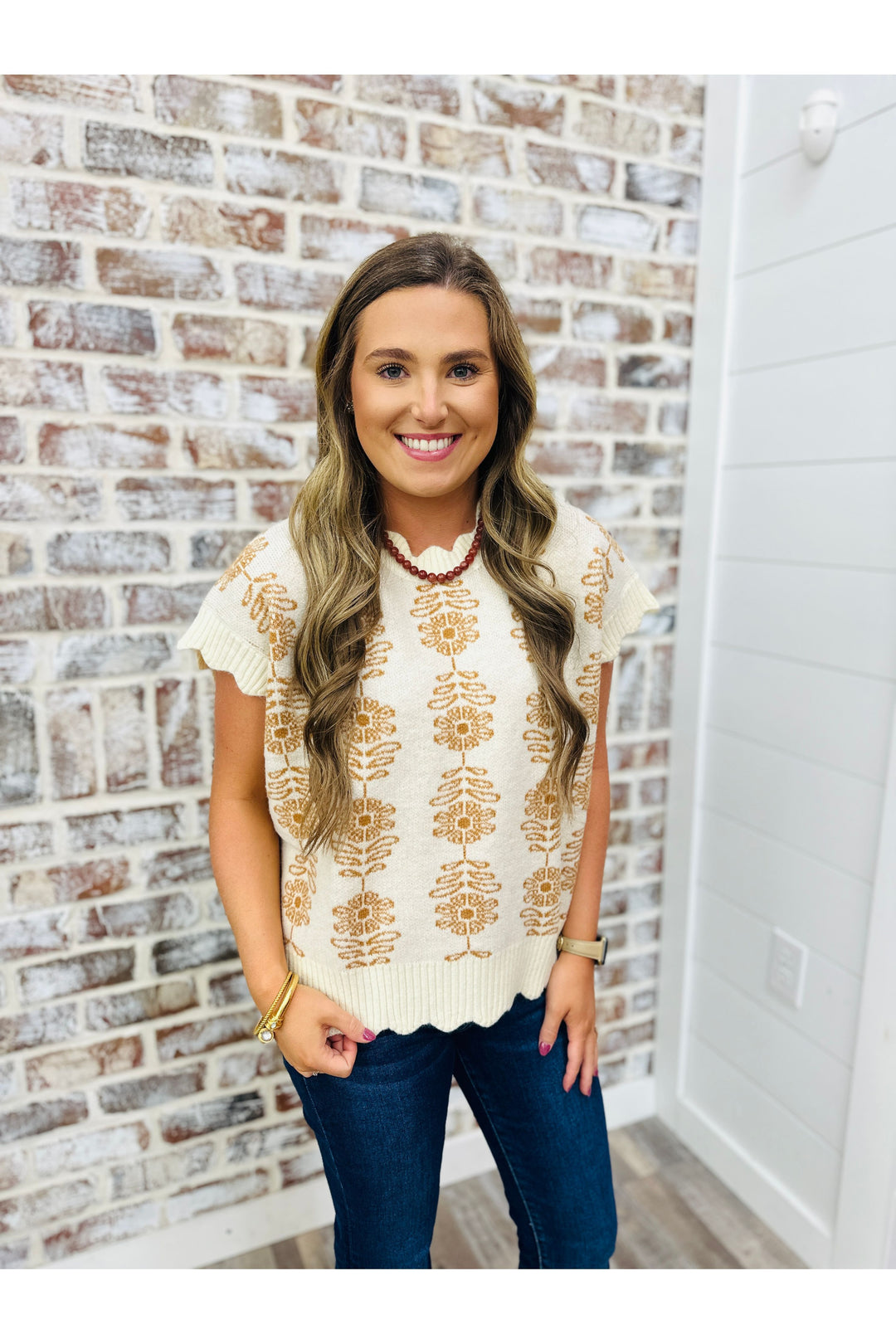 Woman wearing ivory sweater top with floral design 