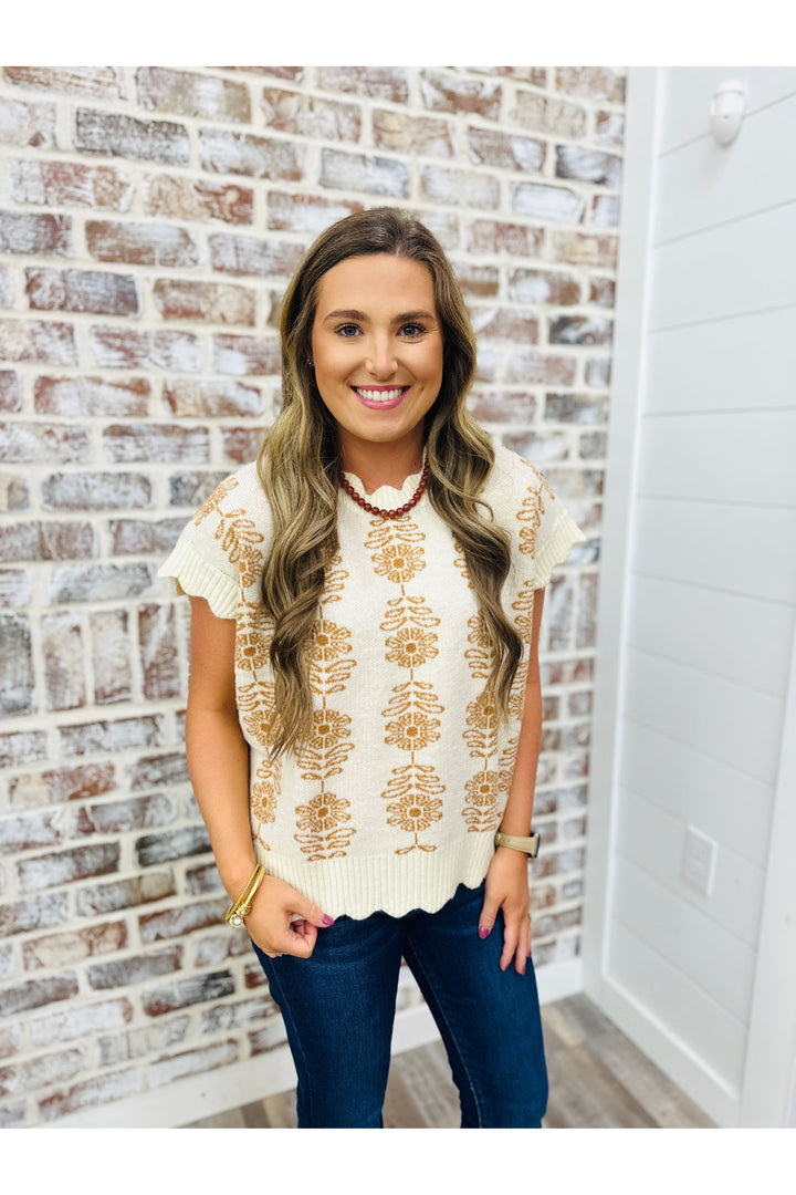 Woman wearing ivory sweater top with floral design 