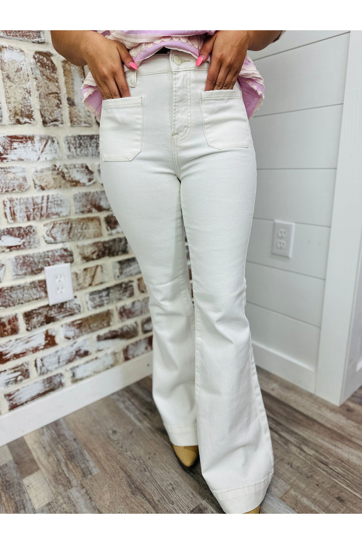 Woman wearing cream high waisted flares with front pocket detail on the front.