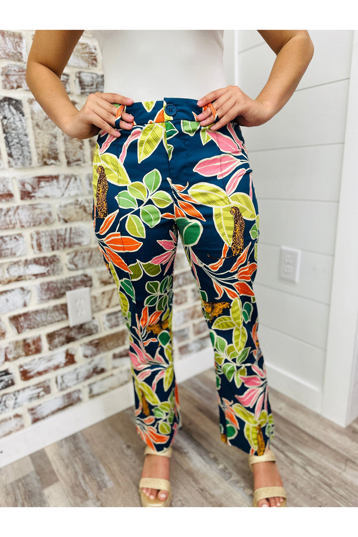 Woman wearing tropical printed pants standing against a brick wall.