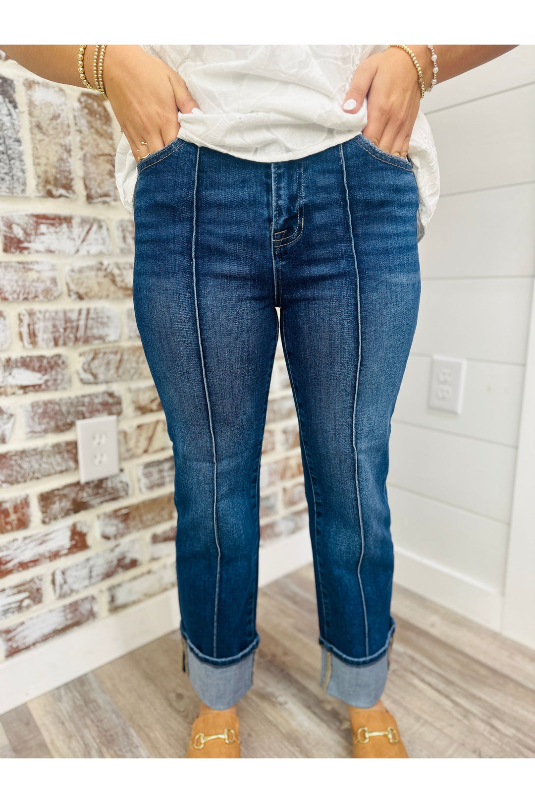 Woman wearing denim jeans with front seam detail standing in front of a brick wall