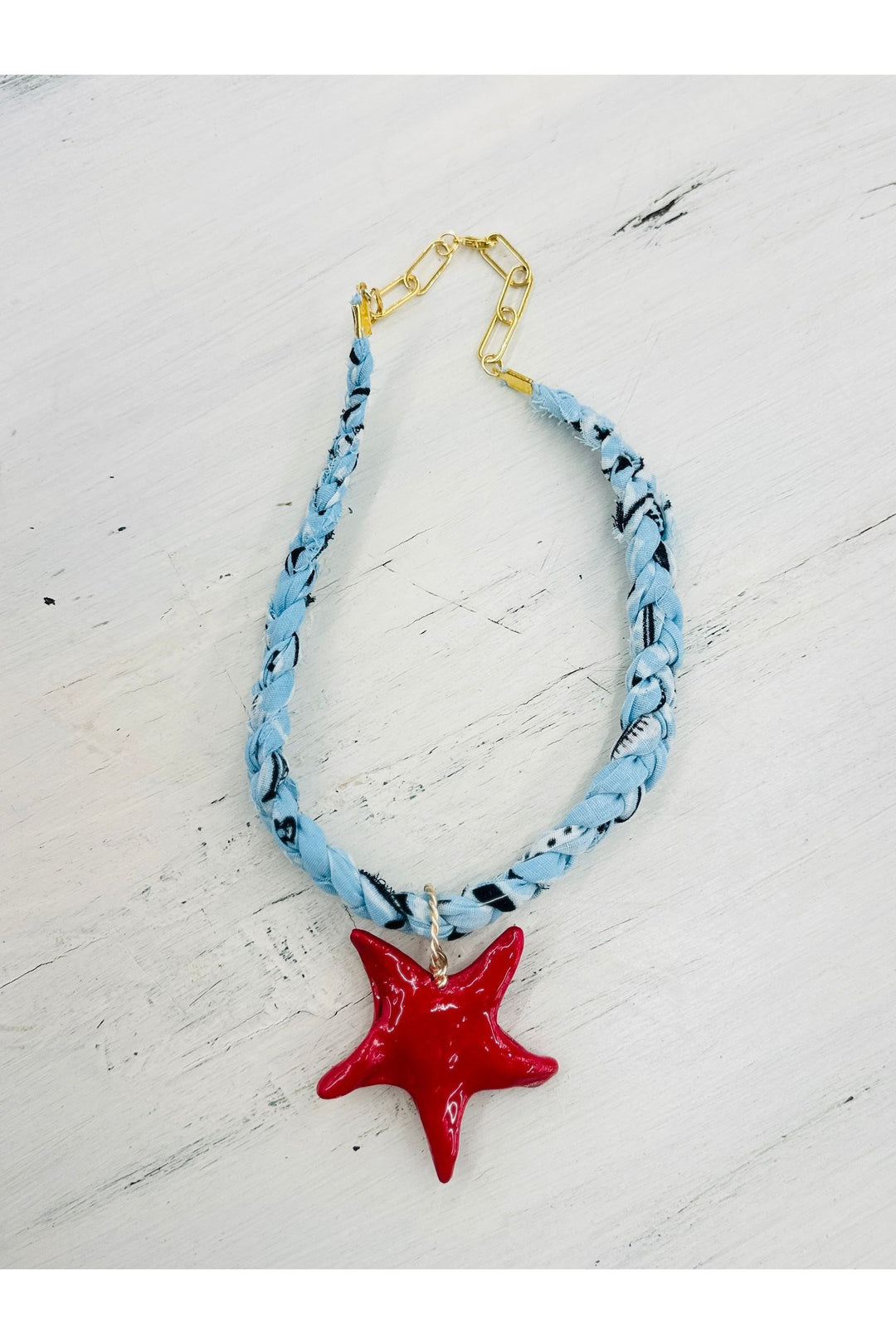 Light blue braided scarf necklace with red star charm.