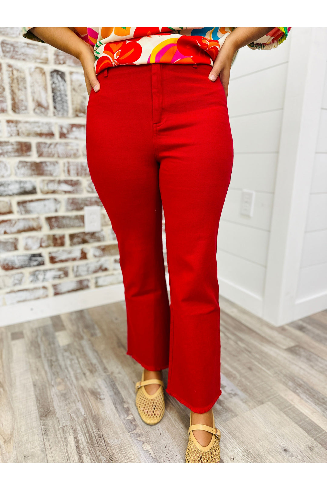 Woman wearing red high waisted flare pants standing against a brick wall.