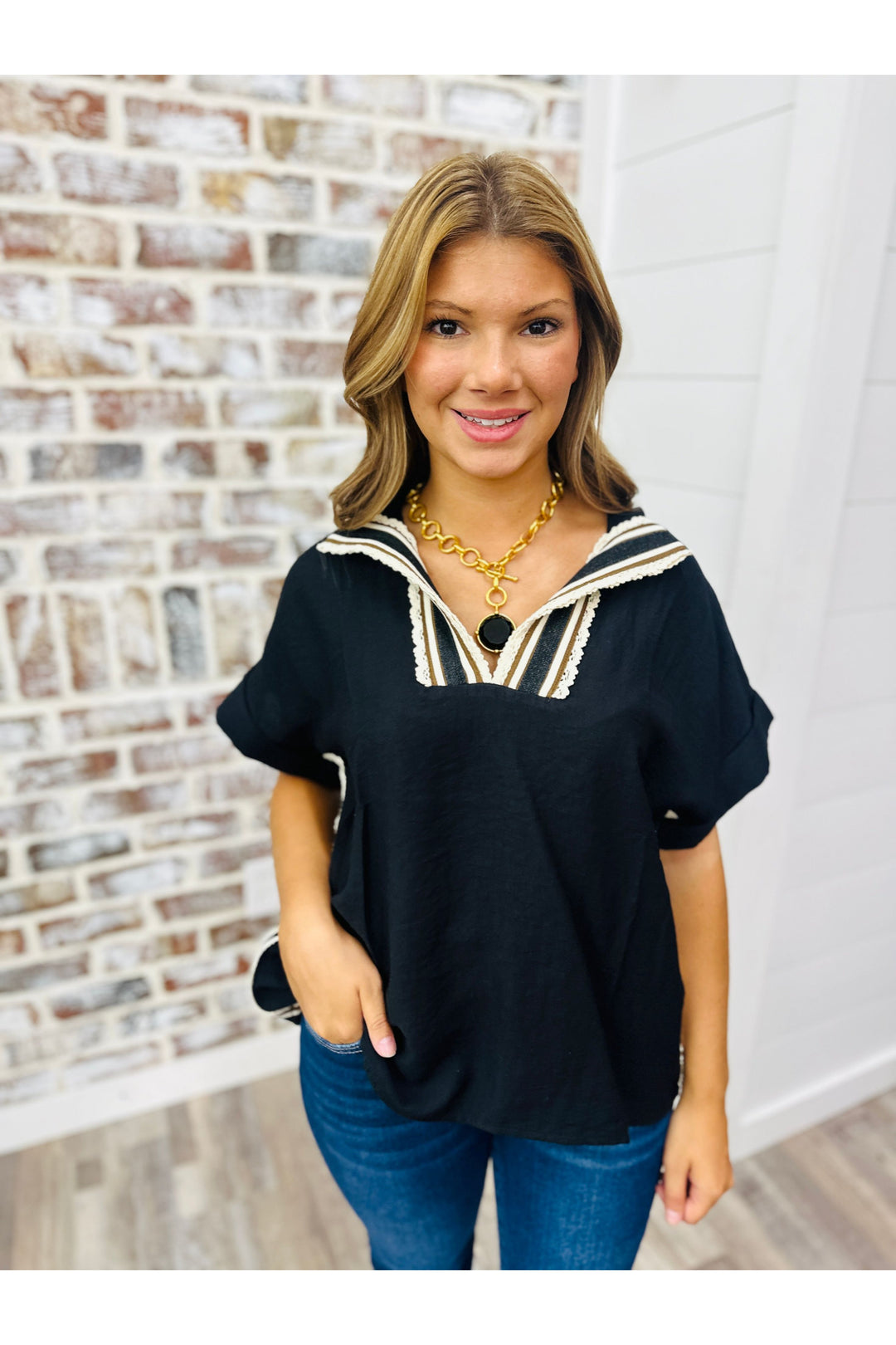 Woman wearing black blouse with crochet detail along neckline. Paired with Julie Vos statement necklace and jeans.