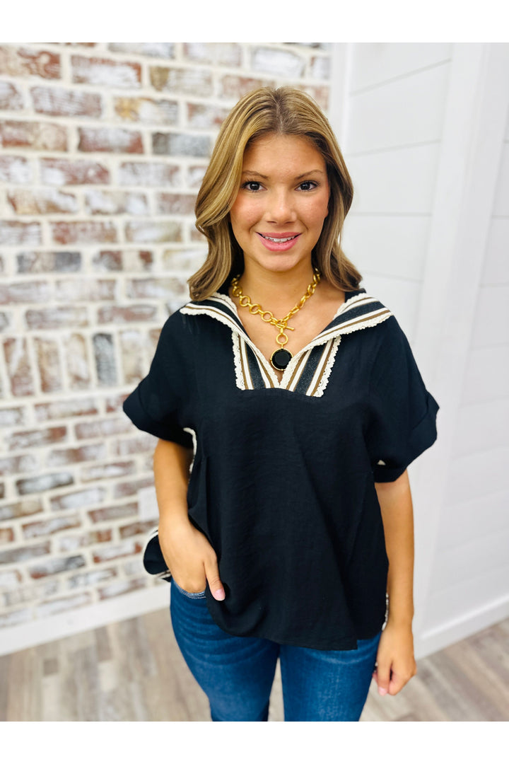 Woman wearing black blouse with crochet detail along neckline. Paired with Julie Vos statement necklace and jeans.