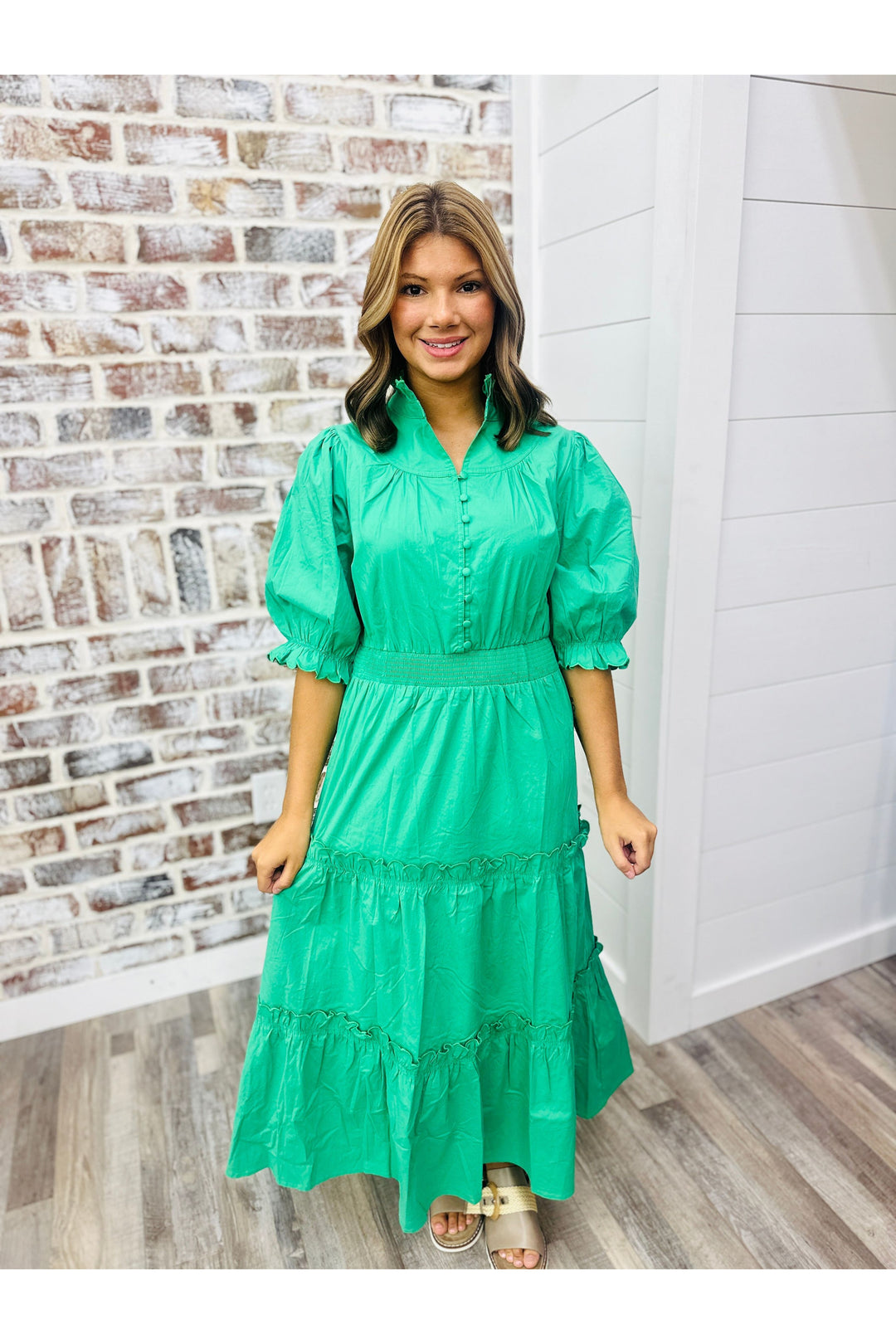 Woman wearing kelly green midi dress with scalloped sleeves and button detail.