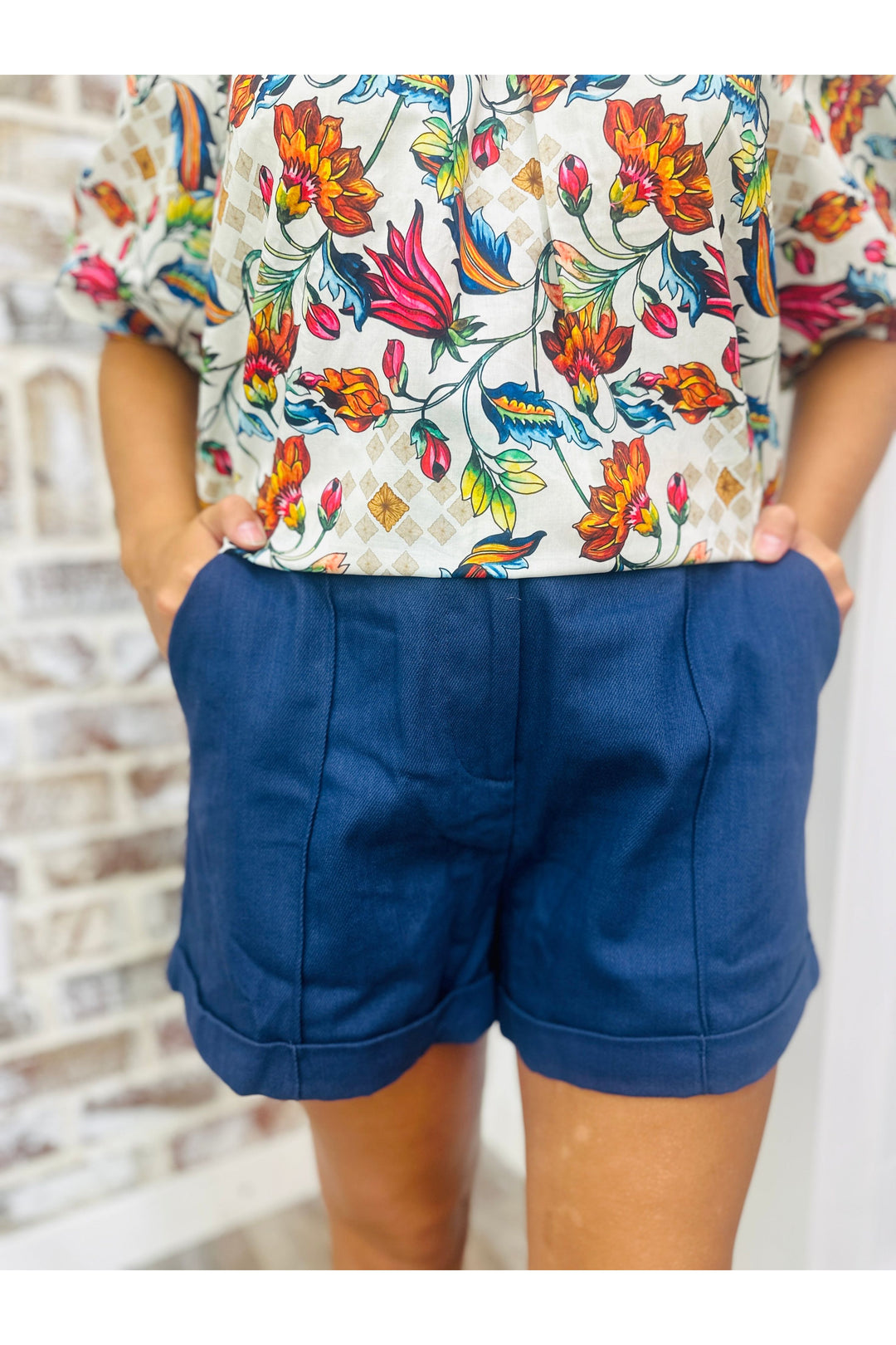 Woman wearing navy blue seamed shorts standing aginst a brick wall.