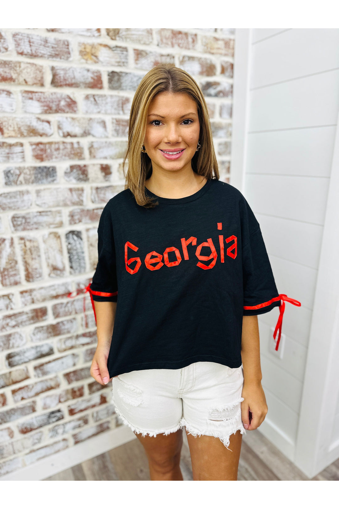 black short sleeve top with Georgia spelled out in red.  Red tie bows on sleeves.