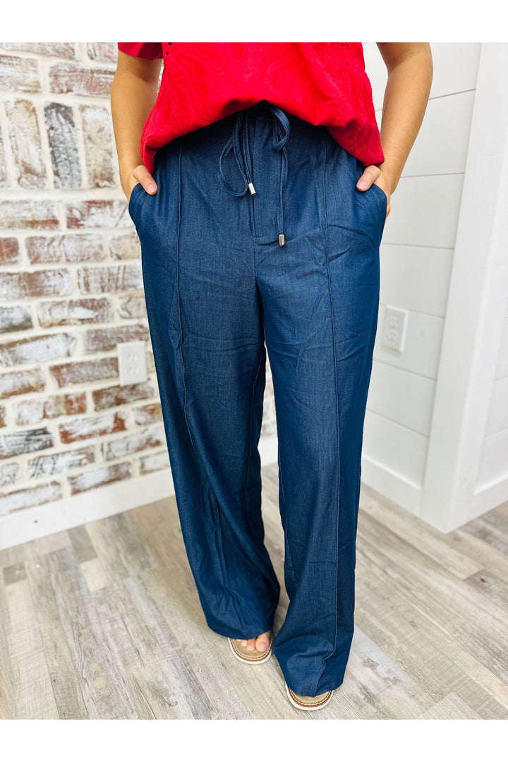 Woman wearing denim trouser pants with string belt detail.