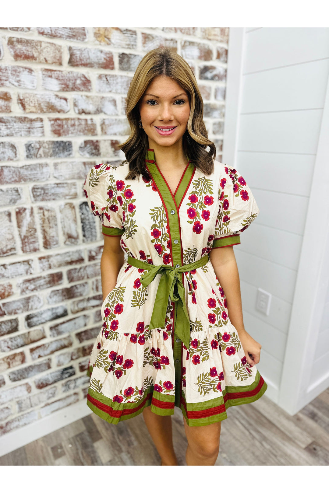 Woman wearing ecru dress with floral detail and colorful trim.