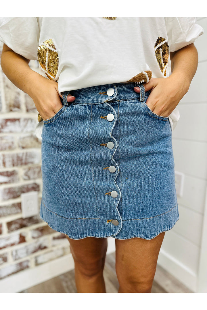 Short denim skirt with buttons down the front and scalloped edges.